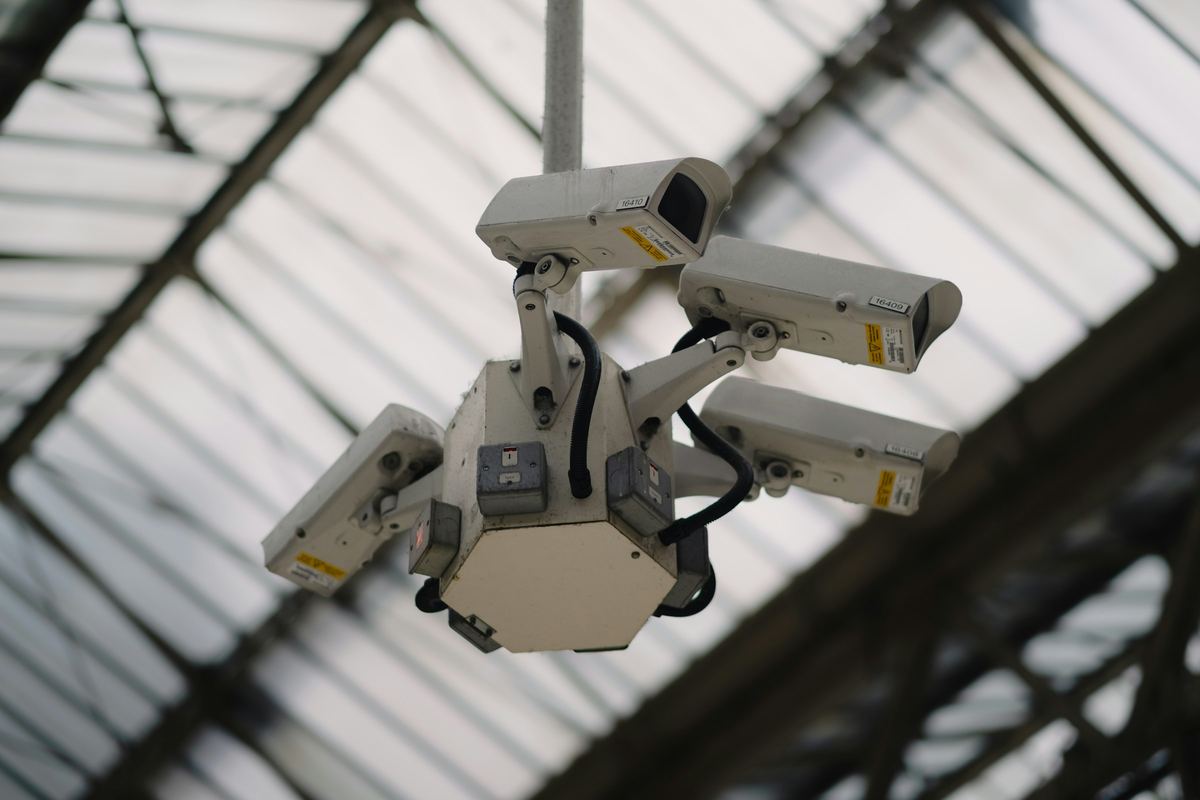 A cluster of CCTV cameras hanging beneath a glass roof in London.