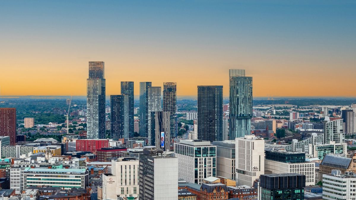 The Manchester city-centre skyline of high-rise towers at sunset viewed from above.
