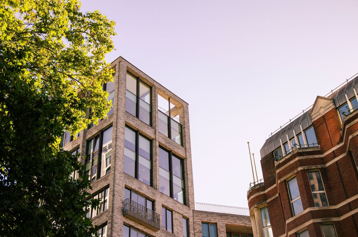 Modern brick office and apartment buildings beside a red-brick mansion block in London.