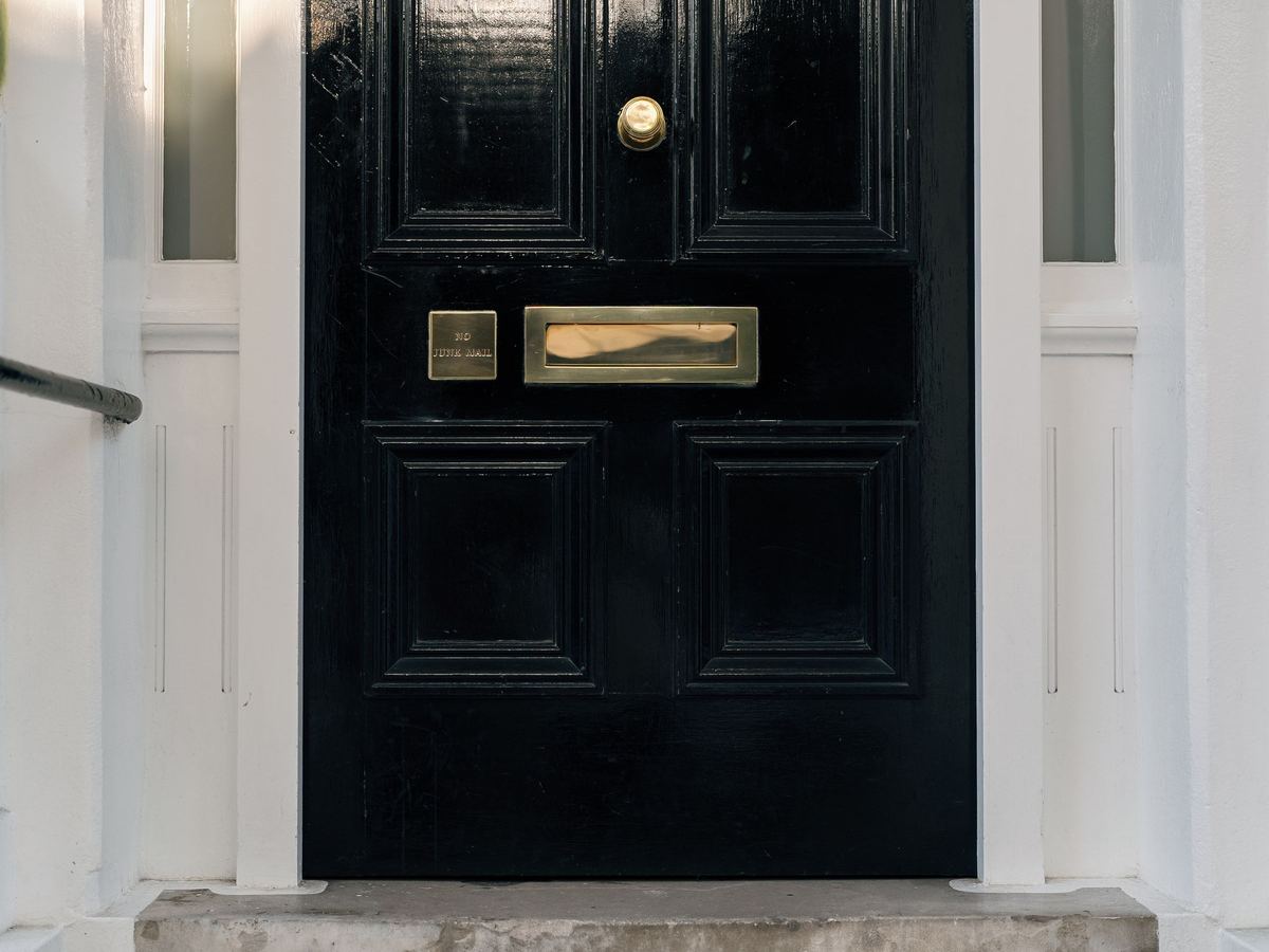 The black front door of a London townhouse with a brass letterbox and knob.