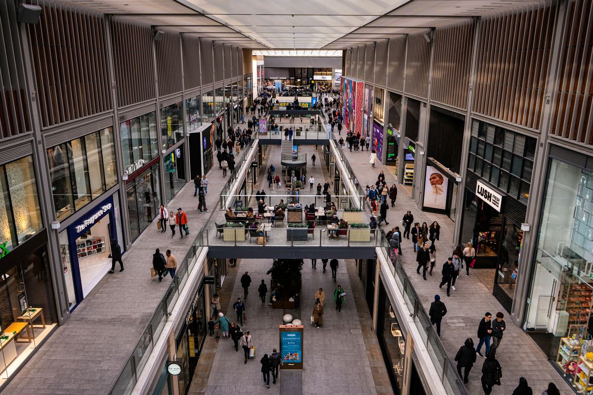 Shoppers on several levels inside a modern shopping centre in Oxford.